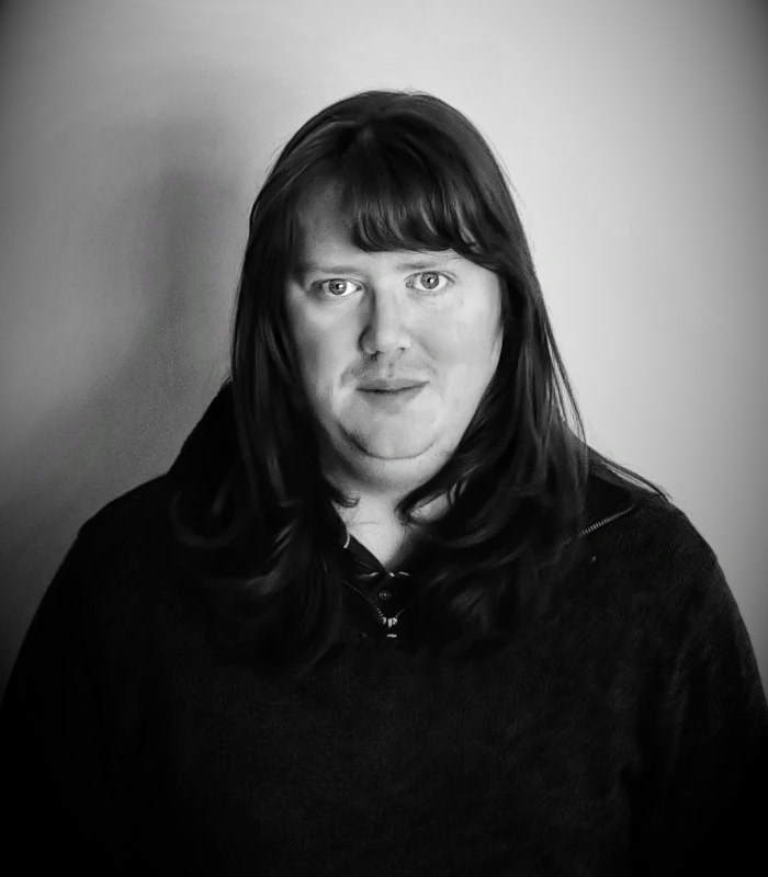 A black and white headshot of James in a wool jumper.